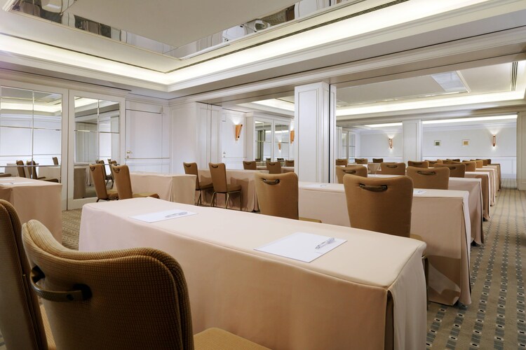 Small conference room with long tables and chairs facing towards a lecturn