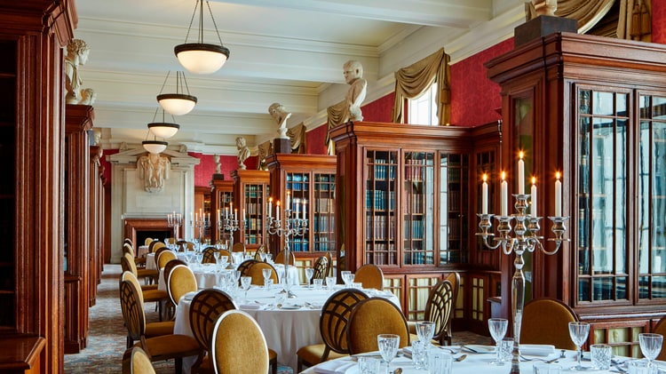 long dining room with round tables and book cases