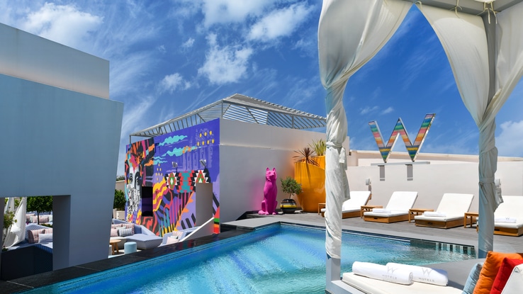 Outdoor WET heated pool with view of WET deck, mural, and outdoor lounge seating. 