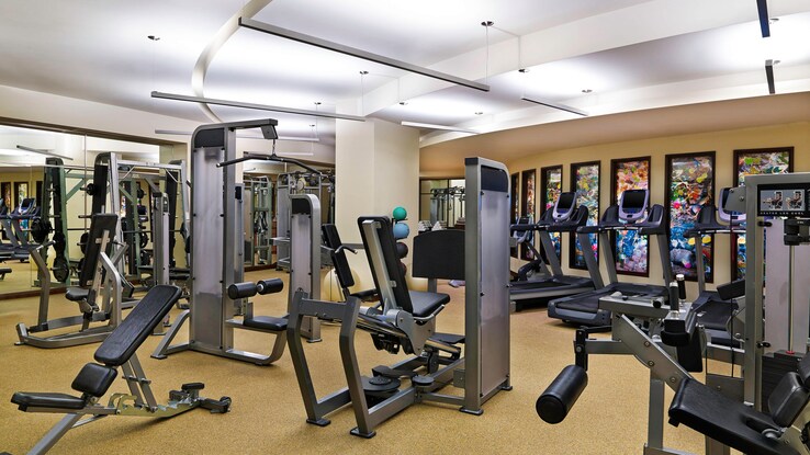 Fitness center with various workout equipment throughout room.