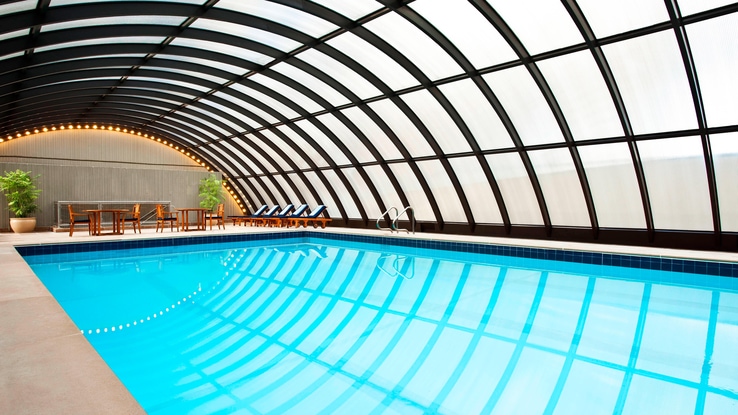 Indoor pool under a translucent glass dome with furniture in a seating area.