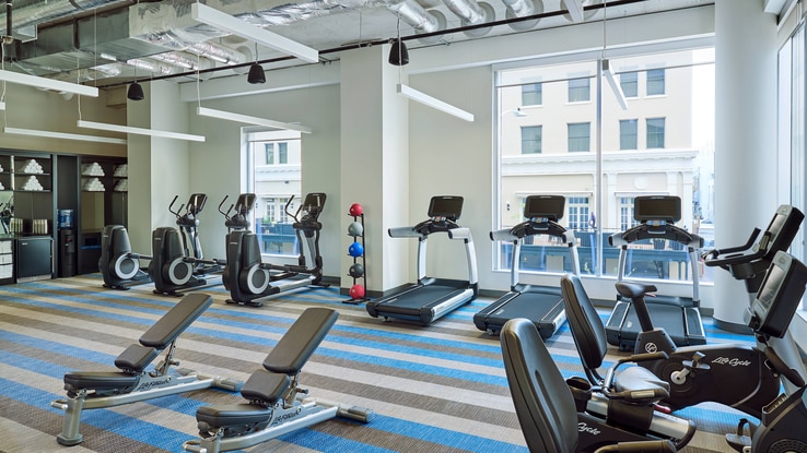A small gym with floor-to-ceiling windows providing a view for its treadmills and bikes.