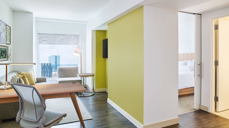 Guestroom featuring workdesk and yellow wall with hallway
