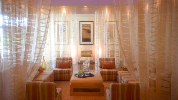 Room with gauzy curtains, couch seating, and atmospheric lighting at The Spa at Desert Springs.