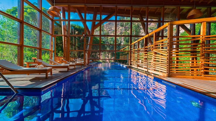 Indoor pool with chaise lounge chairs and large windows