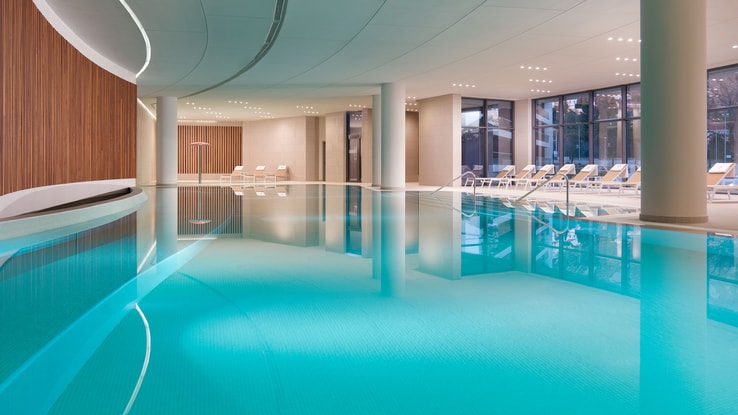 Indoor pool with lounge chairs surrounding it.