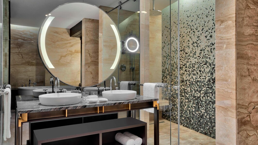 O banheiro da suite Bridal apresenta um elegante piso de mármore e lavatórios, uma banheira de imersão e ducha separada, produtos de higiene pessoal da marca White Tea by Westin™ e um elegante roupão Heavenly.
