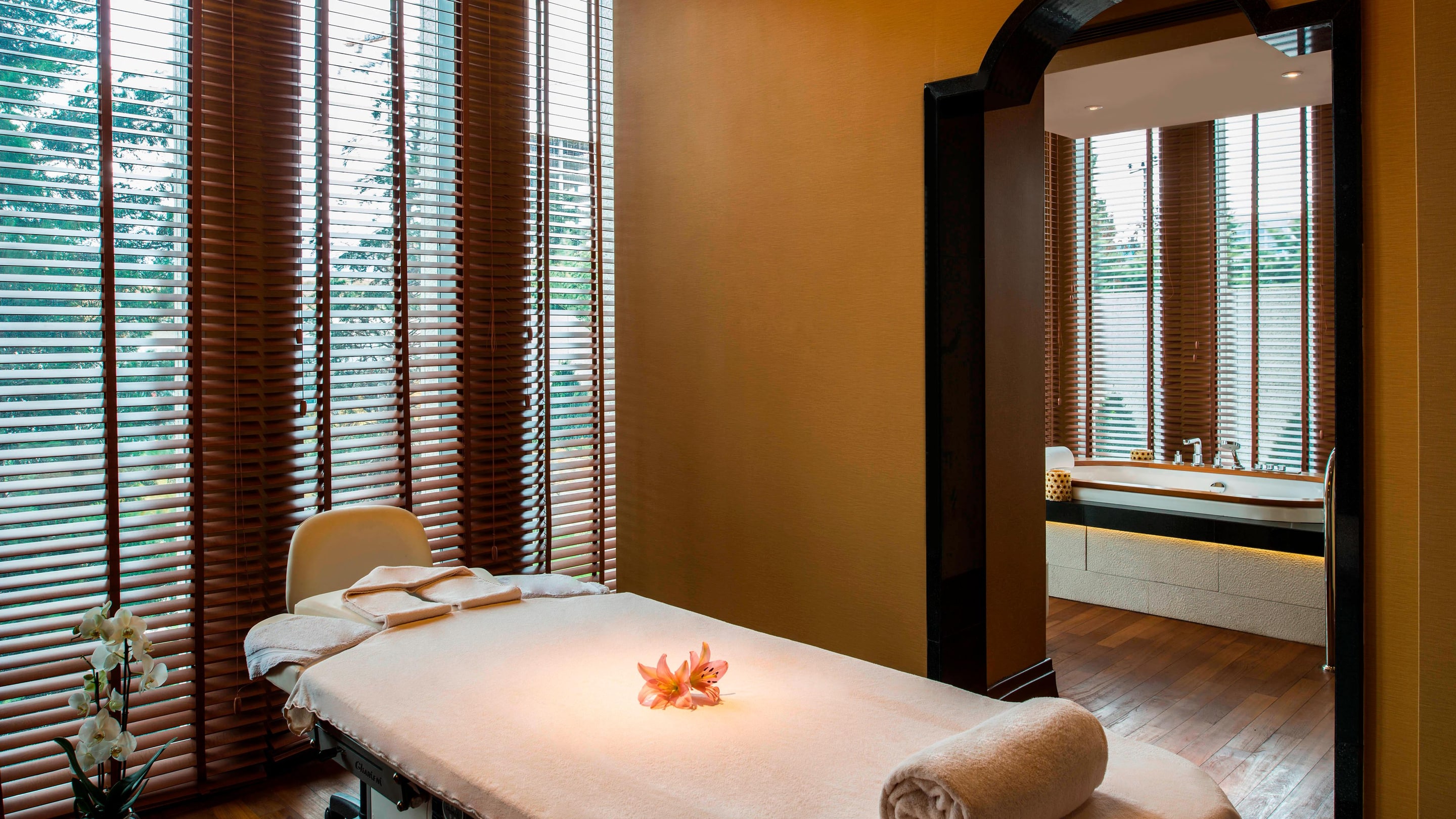 Spa treatment room with a massage table set with towels next to a window.