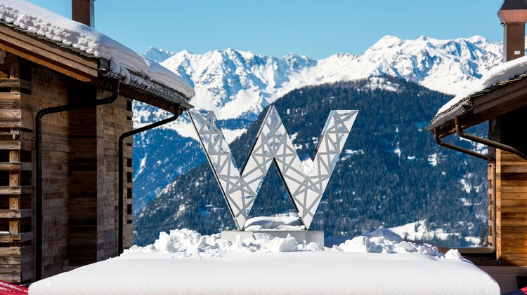 The W hotels logo statue in front of snowy mountains.