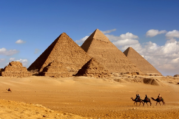 Camel caravan in front of pyramids