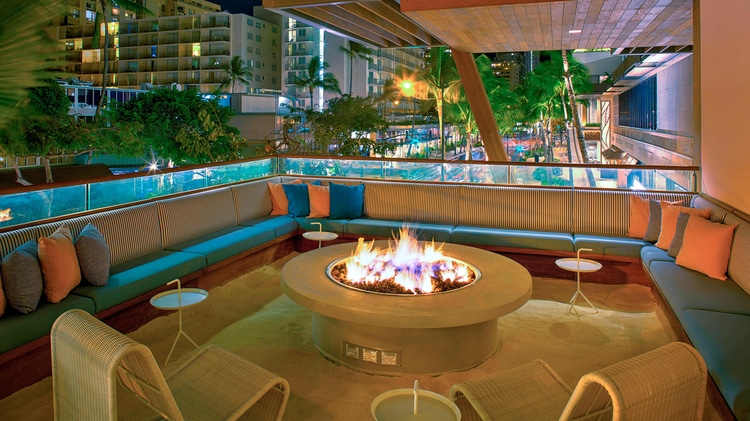 Outdoor terrace with couches all around the room surrounded a fire pit.
