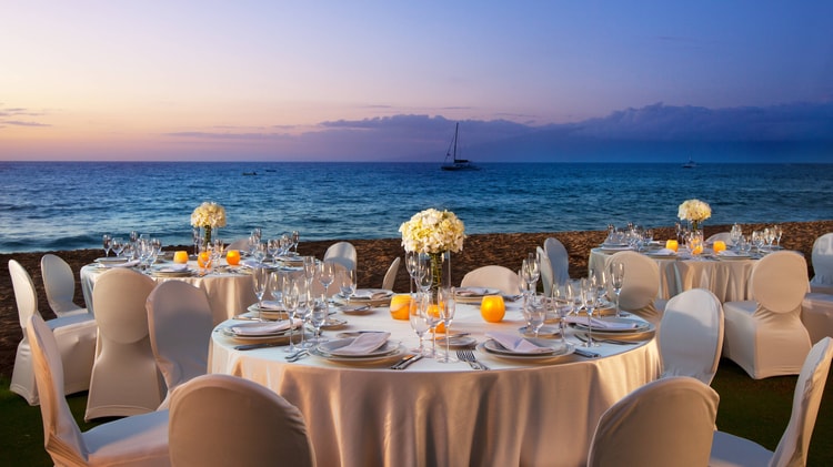 Round tables set with flower centerpieces and view of ocean.