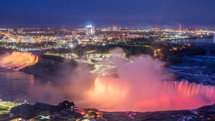 Aerial view of Niagara falls lit up at night.
