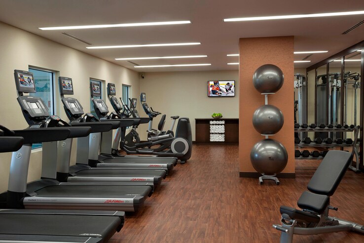 Fitness center complete with a row of treadmills, exercise balls and more.