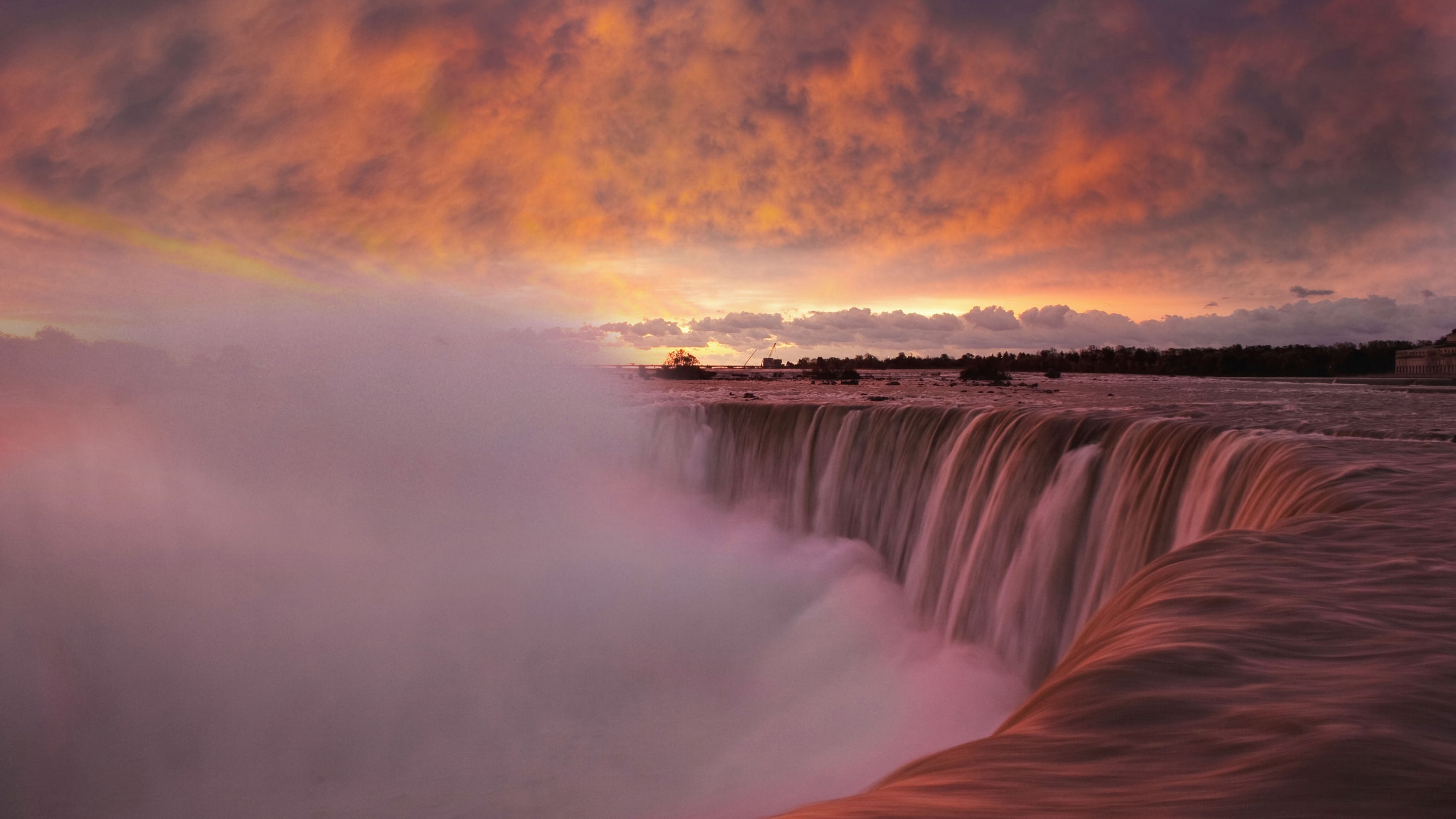 Niagara falls with sunset above it.