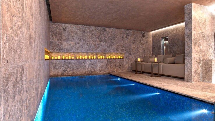 Indoor pool with two lounge chairs set on the side of pool.