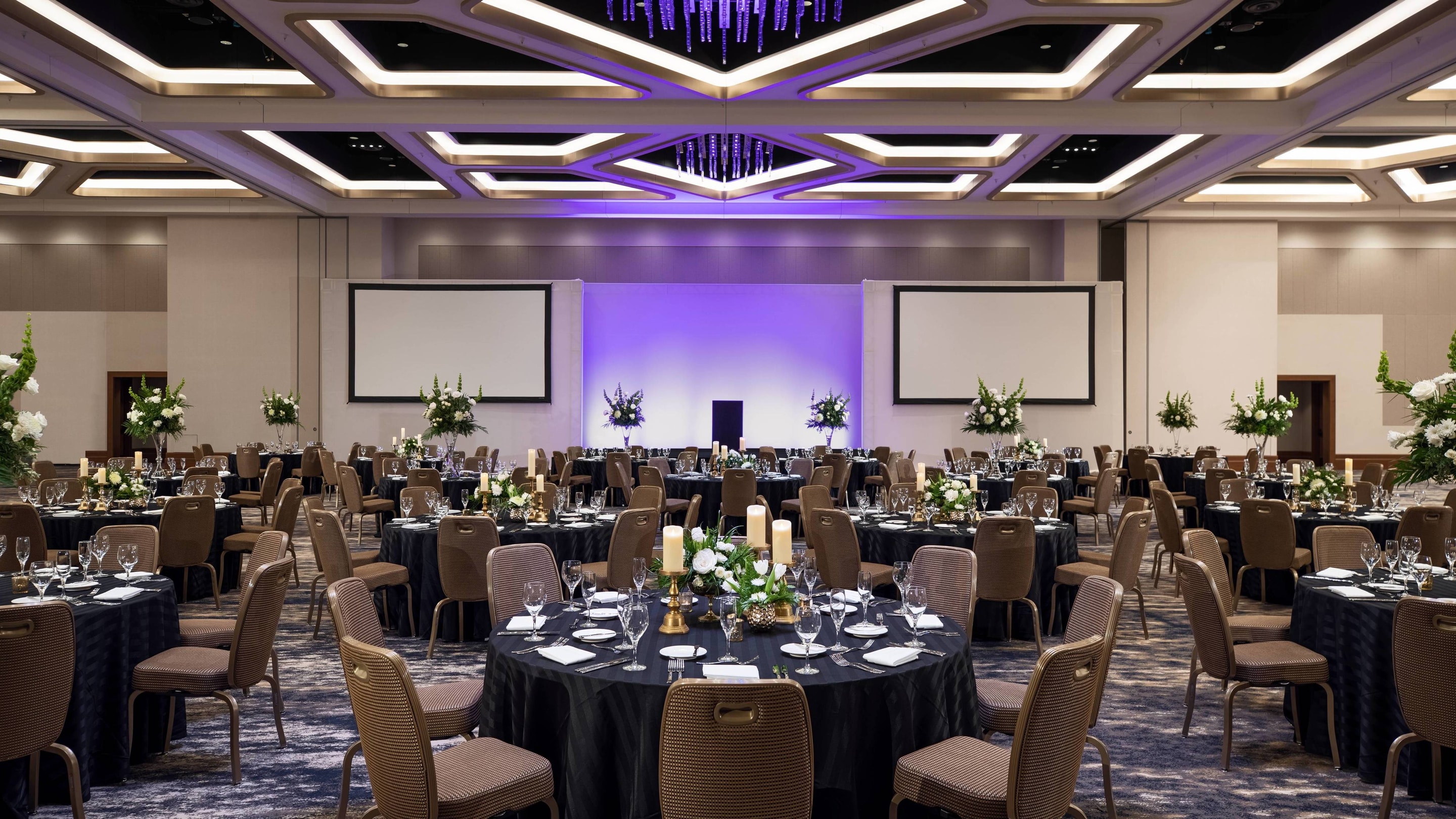 Peninsula ballroom in social setup, with dining tables and chairs.