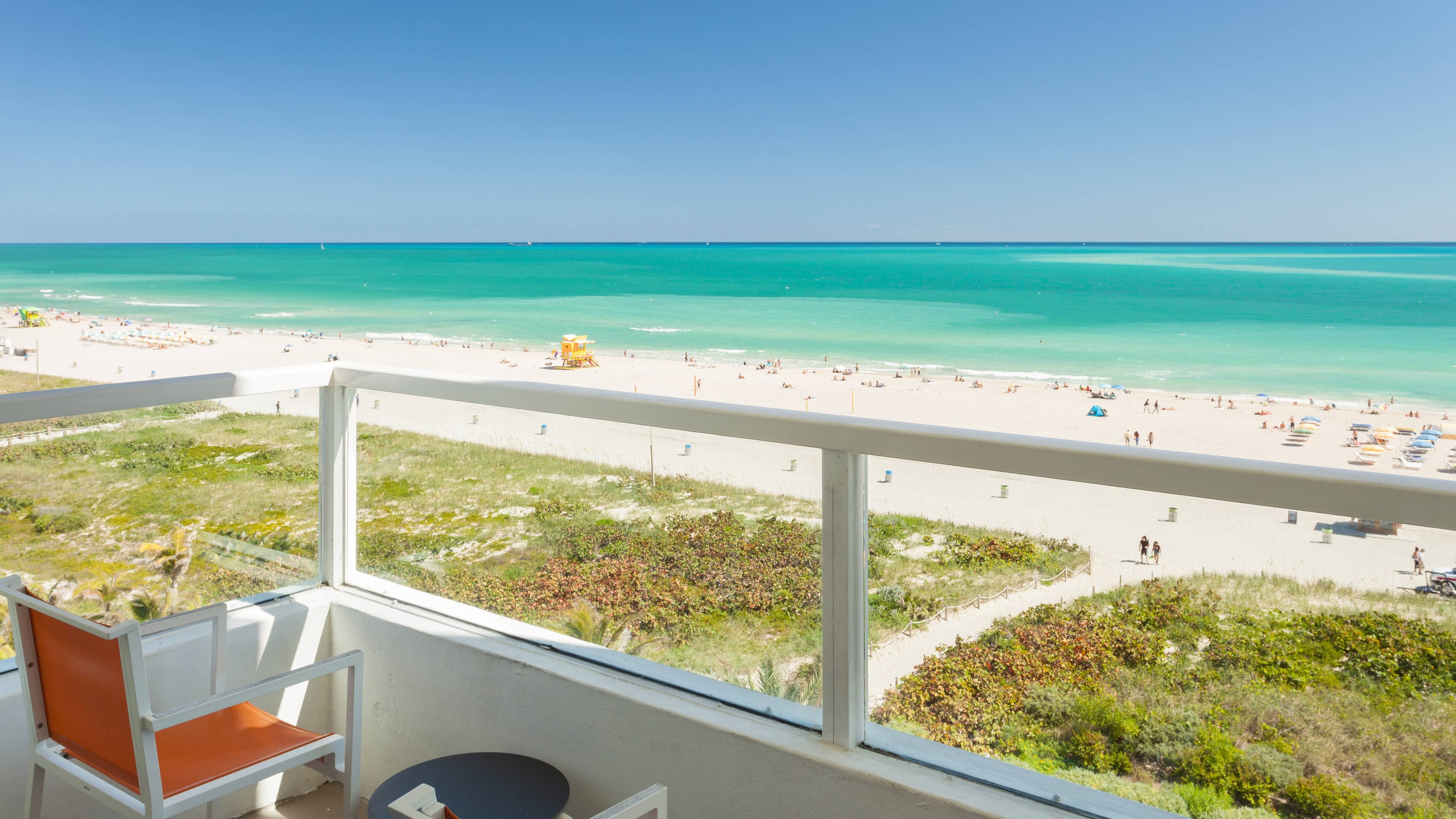 A balcony overlooking a beach next to bright blue water.