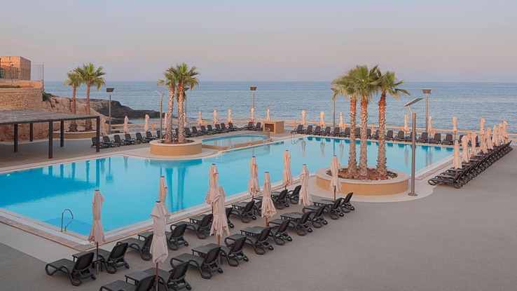 Ample poolside seating covers the sides of the larger Reef Club pool, facing the sea.