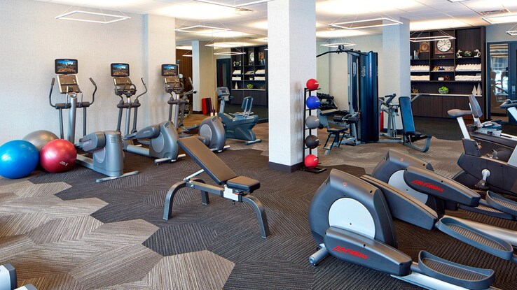 Fitness center with ellipticals and different benches and weights.