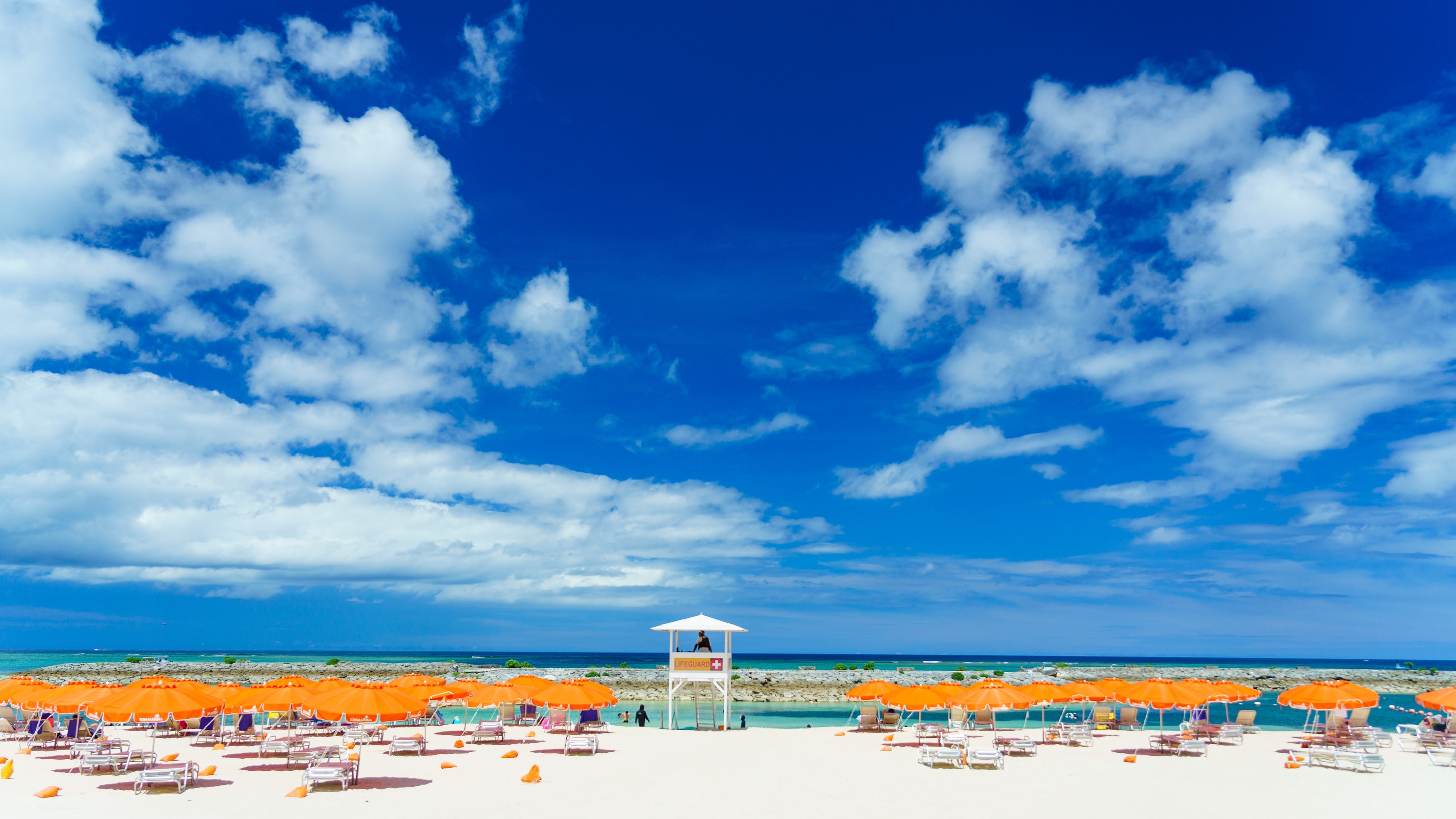 Sunmarina beach with orange umbrellas, blue skies and fluffy clouds
