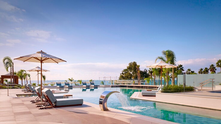 Outdoor lifestyle pool in daytime with umbrellas and chaise lounge chairs