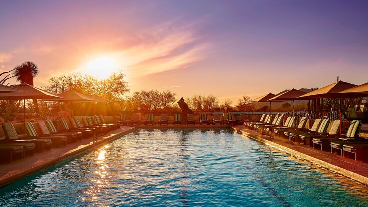 Outdoor pool with chairs at sunset