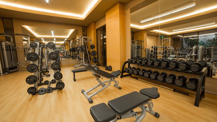 Fitness center with equipment and weights throughout room.