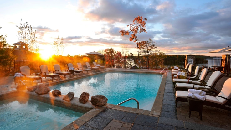 Outdoor spa area at sunset with two pools and several chaise lounge chairs