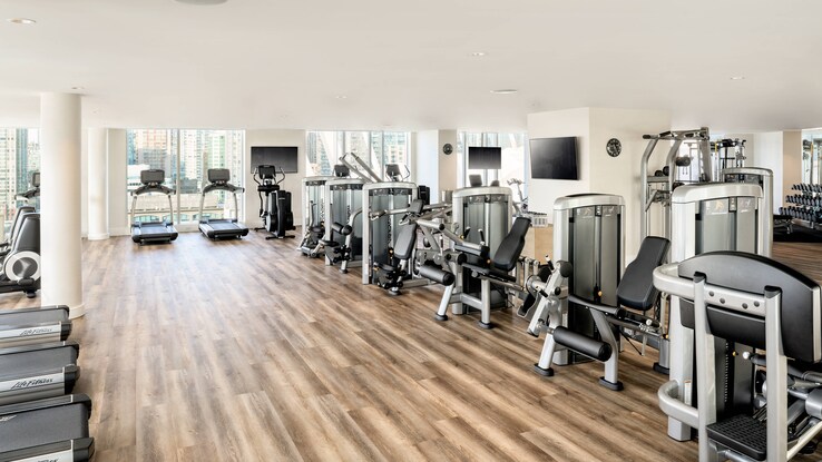 Fitness center with row of treadmills along wall and other equipment.
