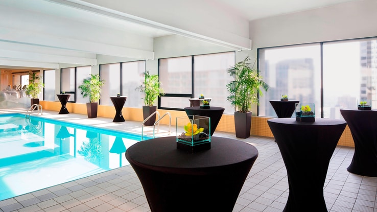 Small round standing tables with miniature terrariums adorn the edges of the heated indoor pool, with wide windows overlooking the city.