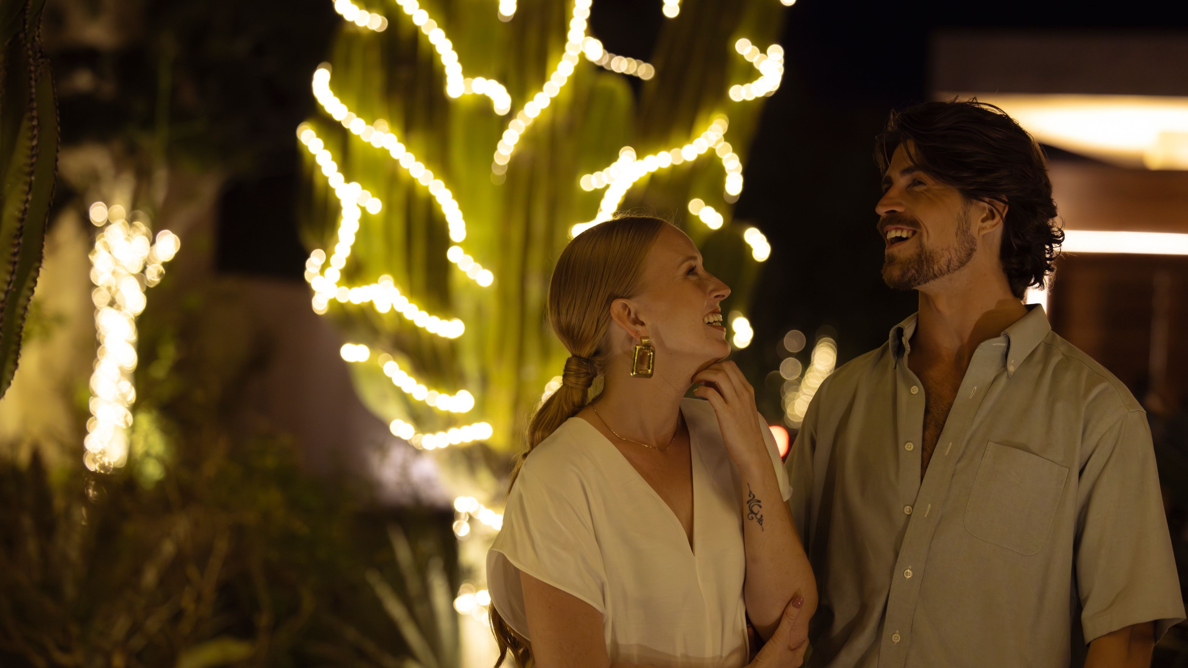 pareja riendo por la noche frente a un cactus iluminado