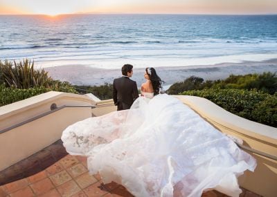 Bride and groom descend stairs toward the ocean