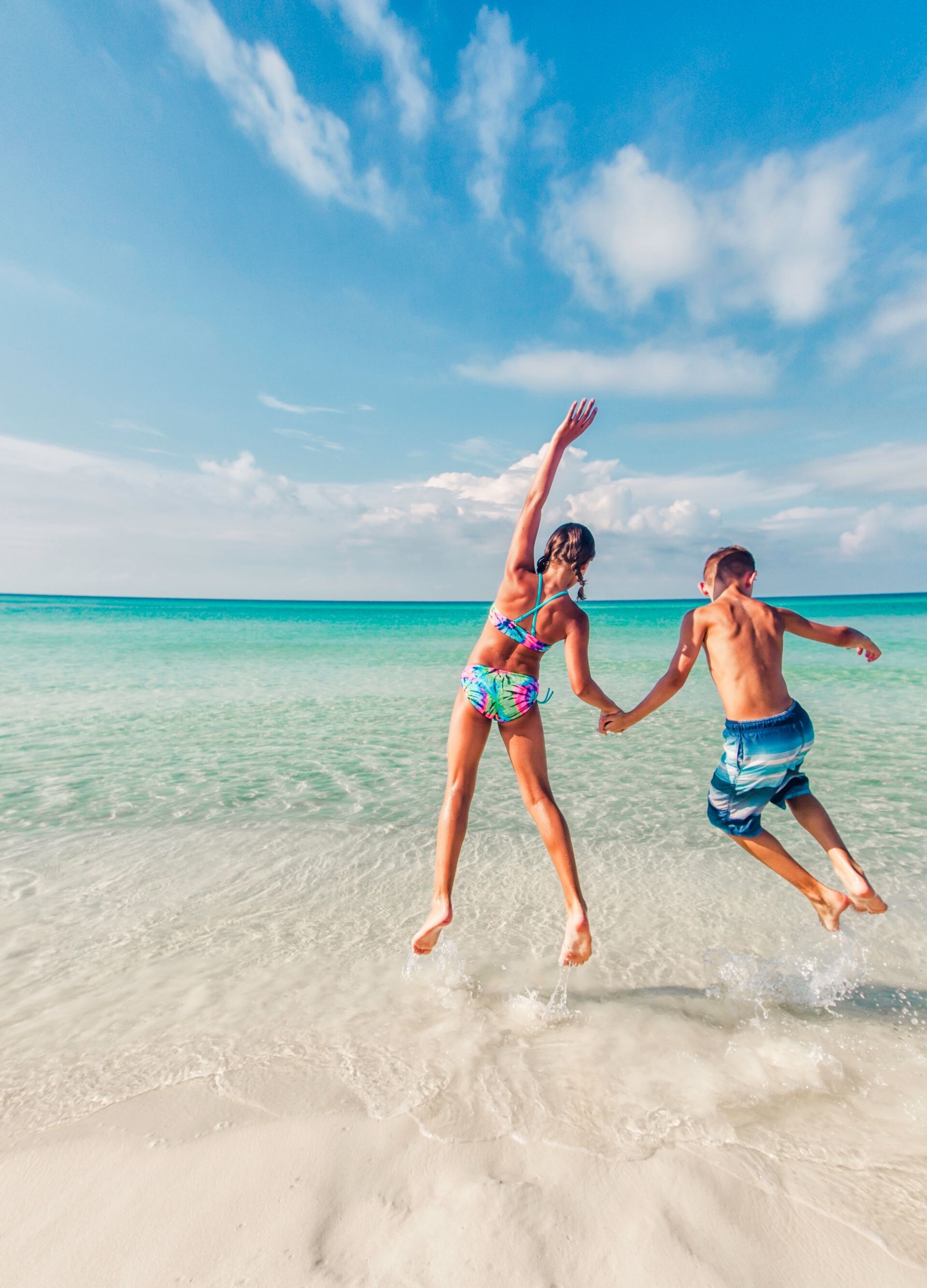 boy and girl jumping in the surf of the Gulf of Mexico