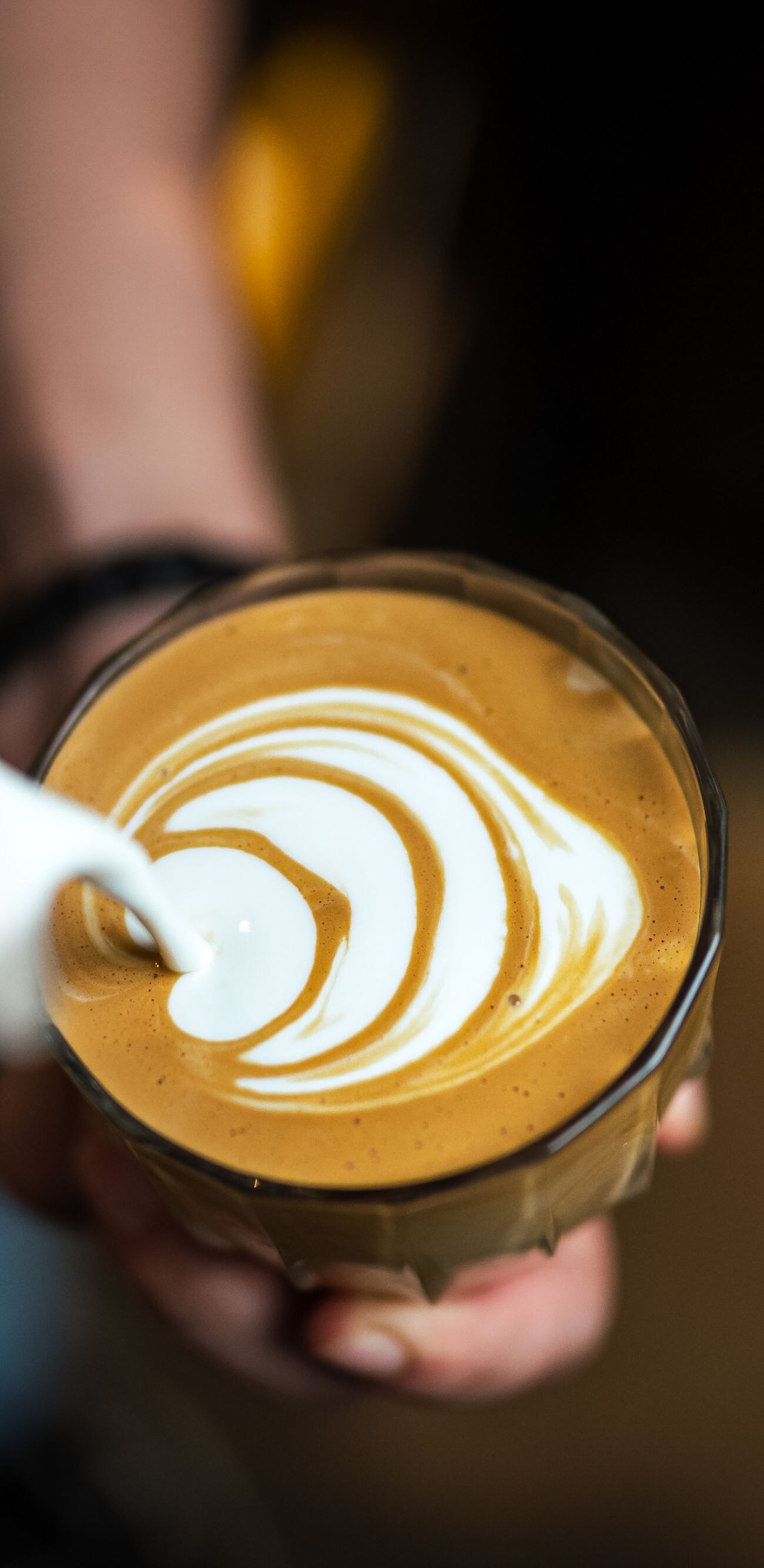 Close up of hand pouring coffee latte art