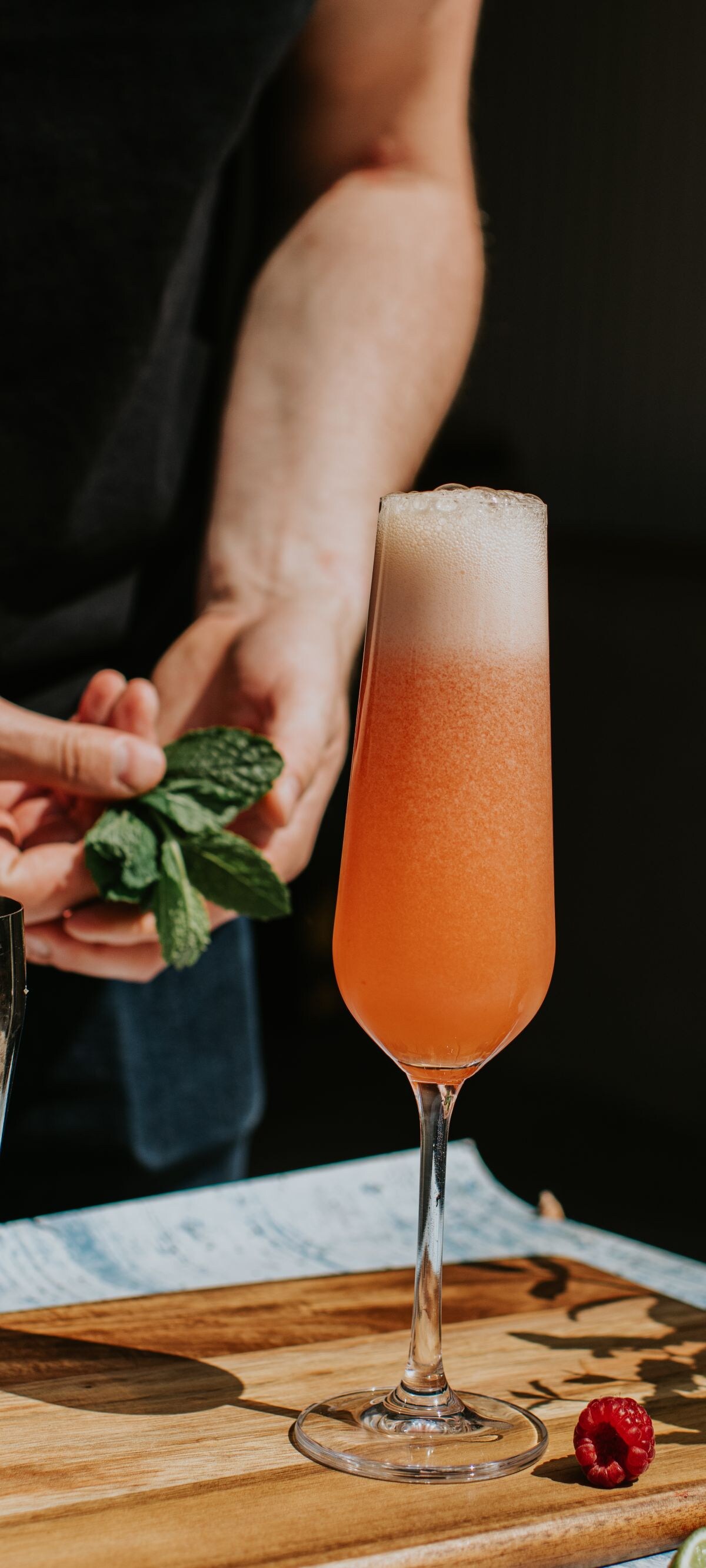 A mixologist prepares a delicious fruit cocktail, garnished with mint.