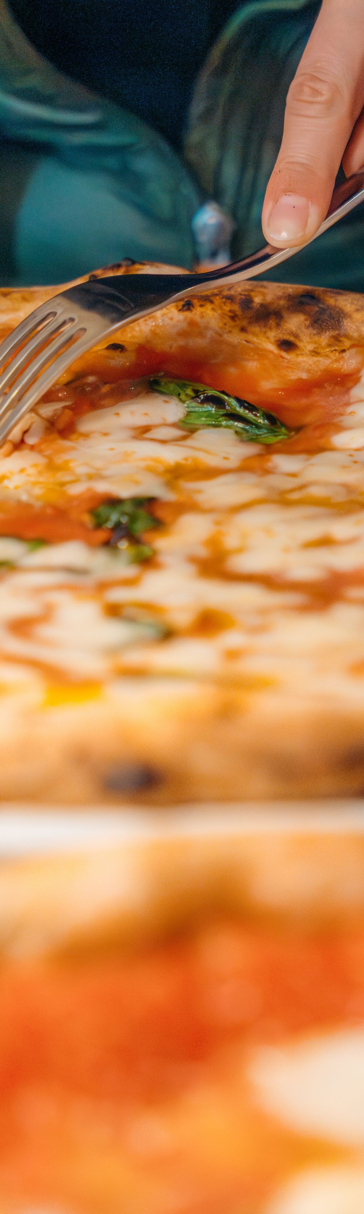 Person cuts pizza slice, enjoying meal.  Delicious food concept.