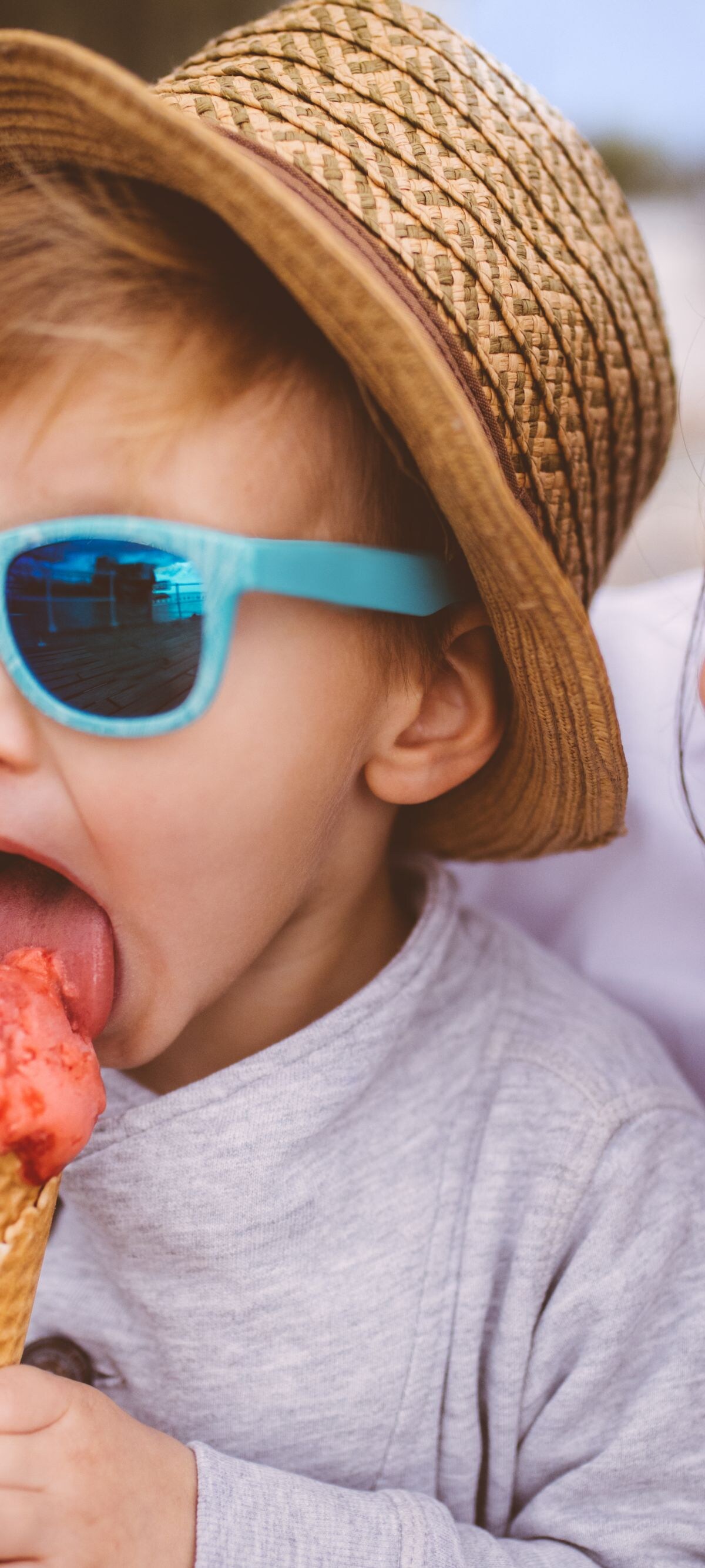 Cute young boy eating ice cream in his mother's arms