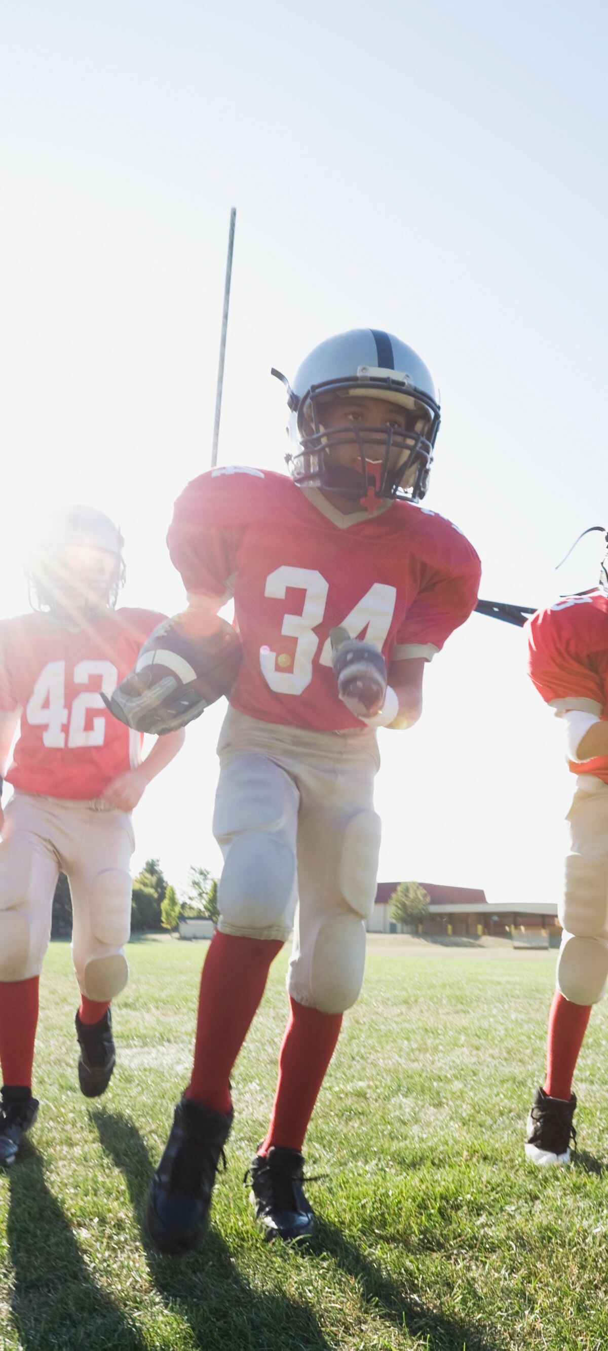 10-11 years, african ethnicity, athlete, back lit, blue sky, boy, caucasian, challenge, childhood, clear sky, color image, competition, copy space, day, energy, five people, football, football field, front view, full length, game, helmet, horizontal, lens flare, mixed race person, motion, multi-ethnic group, only boys, oregon, outdoors, people, photography, player, playing, portland, pre-adolescent child, running, sports, sunny, team, teammate, teamwork, together, uniform