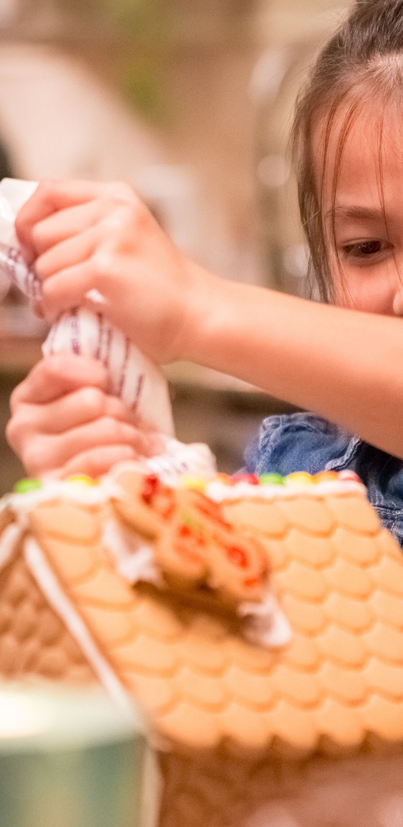 Little girl decorating Christmas gingerbread house