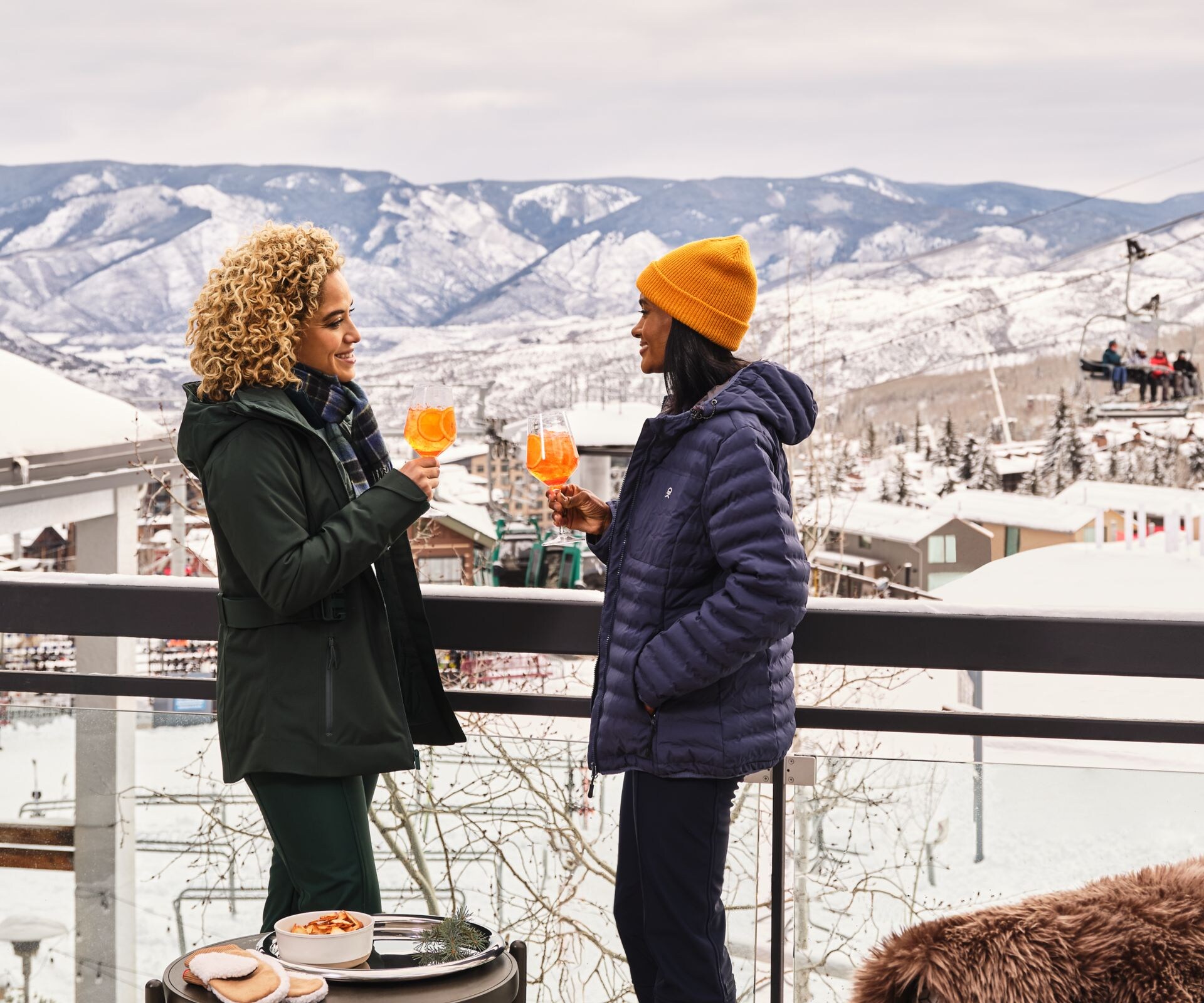 Two women with drinks on snowy terrace