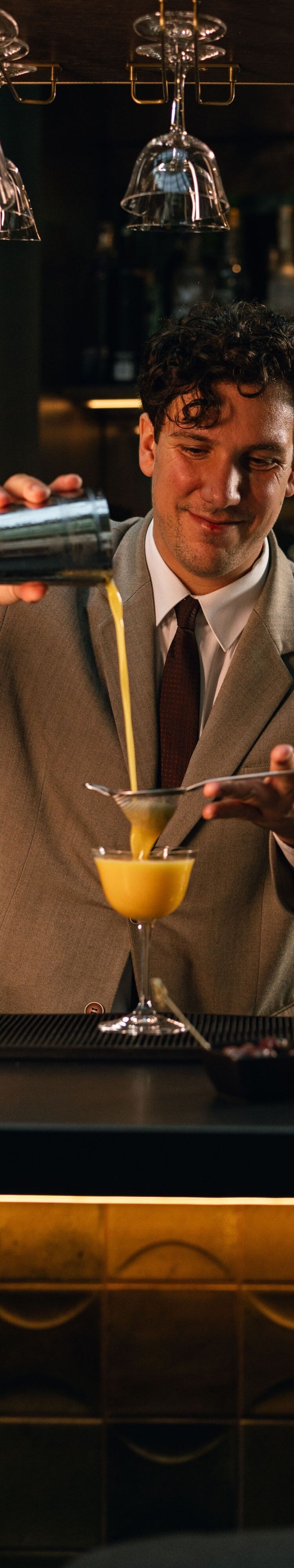 A bartender carefully pours a freshly prepared coc