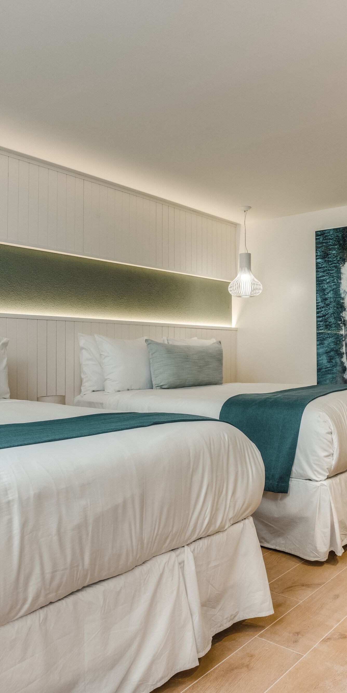 Two queen beds with teal accents