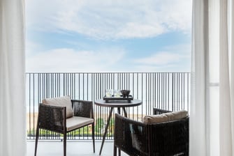 balcón con mesas y sillas y vista al mar
