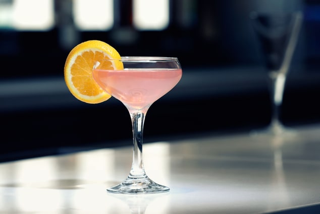Pink cocktail with orange garnish