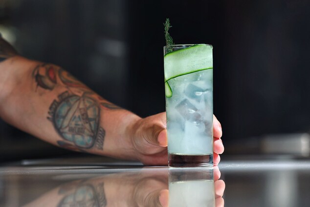 Hand Holding a Cocktail with Cucumber Garnish
