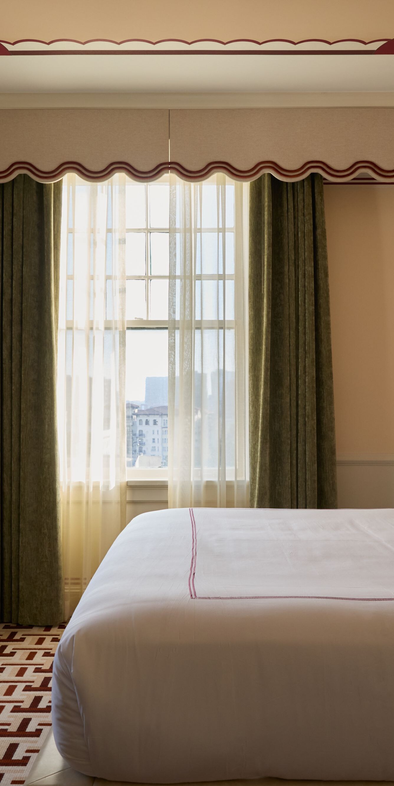 King bed beside tall sunlit windows