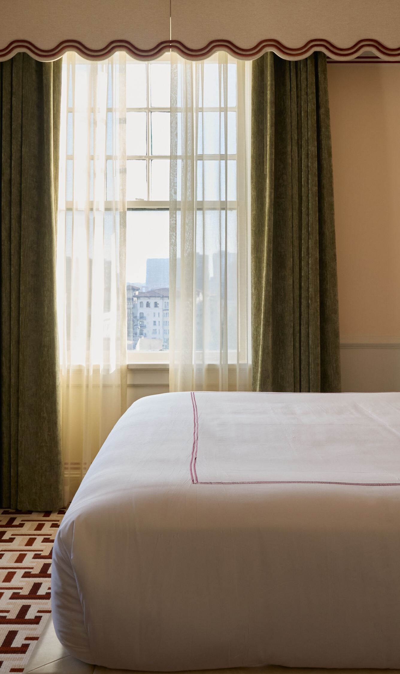 King bed beside tall sunlit windows