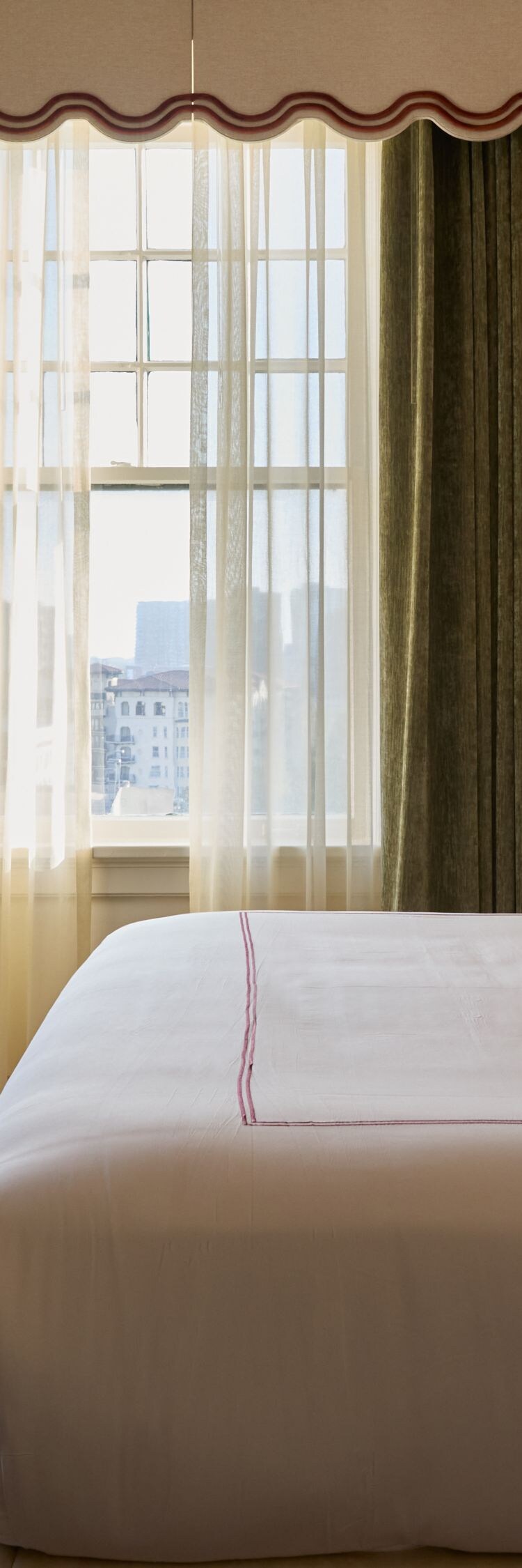 King bed beside tall sunlit windows
