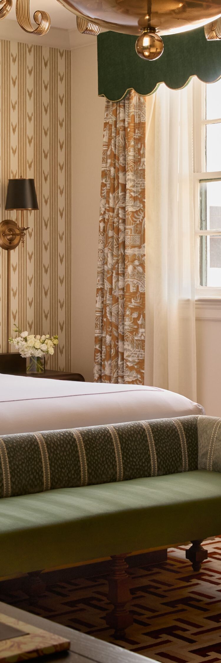 Guest room with king bed, bench, and chandelier